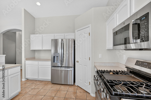 White kitchen interior with stainless steel refrigerator oven, microwave, and spacious big cabinetry