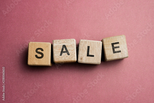 Wooden letter blocks spelling SALE on a red background with minimalist composition and copy space.