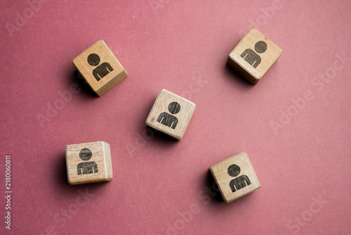 Five wooden blocks with person icons arranged on a red background, representing users, people, customers, community, teamwork, and social connection, with minimalist composition and copy space.