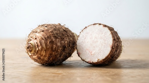 Whole and sliced taro root on a wooden table, a tropical starchy root vegetable used in various culinary dishes and desserts, closeup view