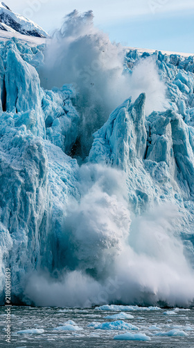 Glacier Calving in Arctic Ocean: A colossal glacier dramatically calves into the frigid waters of the Arctic Ocean, sending massive chunks of ice crashing down in a powerful display of nature's force.