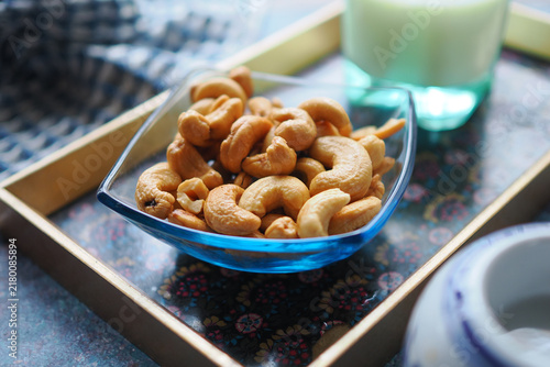 Cashew nuts in a glass bowl on a wooden tray