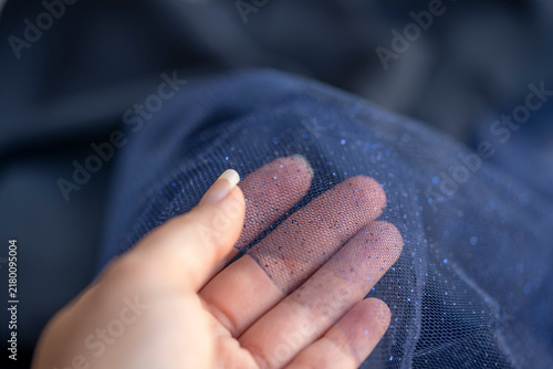 mano de mujer mostrando transparencia de tul con brillantina azul