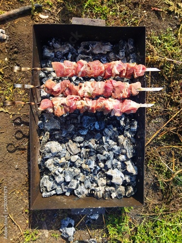 Принти на полотні meat on the grill,Top-down view of three metal skewers loaded with raw pork shis