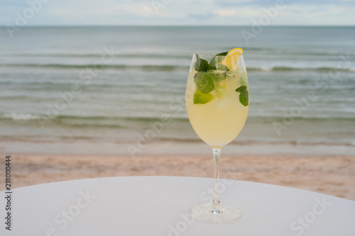 Yellow cocktail with lemon on a table at the beach.