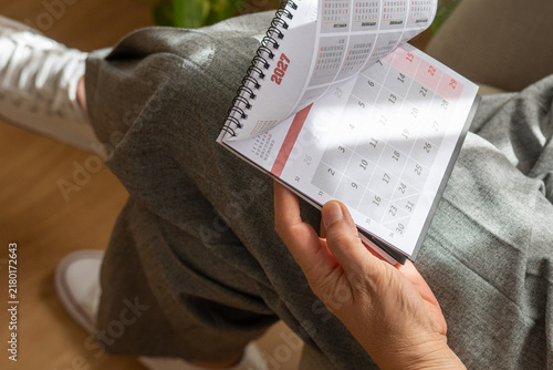 Obraz na plátně Person's hand flipping through a spiral-bound desk calendar for the year 2027, l