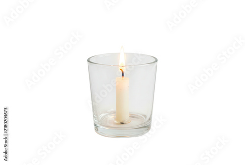 Single white candle burning inside a clear glass holder on black background