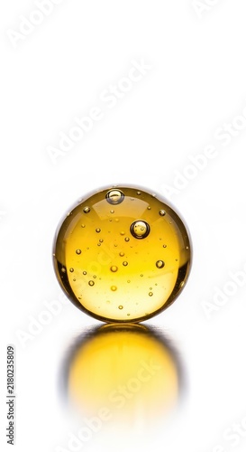 A translucent golden yellow oil droplet containing small air bubbles, isolated on a white background with realistic reflections and shine, ingredient, olive oil, texture