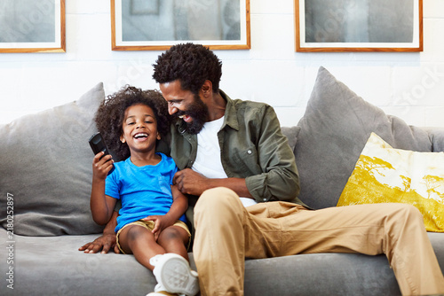 Obraz na plátne Dad, child and laugh or watching tv in home living room with comedy movie, happy and cartoon show