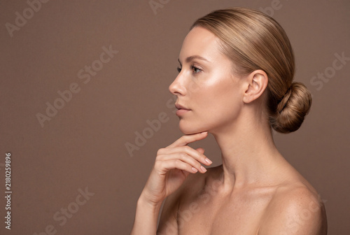 Profile portrait of a beautiful young woman with clean skin and elegant hair bun