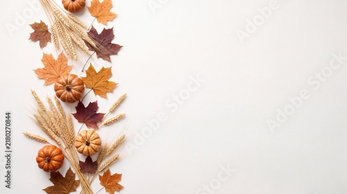 A beautiful vertical border made of dried wheat stalks colorful autumn leaves and small pumpkins on a white background for a festive thanksgiving holiday season