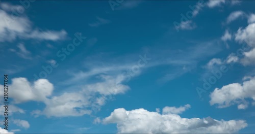 Time lapse of fluffy white cumulus clouds moving rapidly across a clear blue sky on a bright sunny day