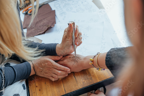 Obraz na płótnie Close-up of an artist applying a temporary henna-style sun design to a person’s
