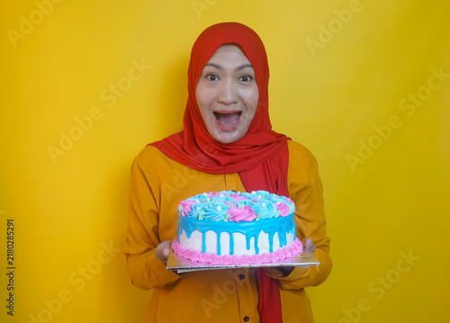 Image Of Cheerful Young Woman With Hijab Making Wish And Showing Surprise Expression While Holding Birthday Cake Isolated Over Yellow Background