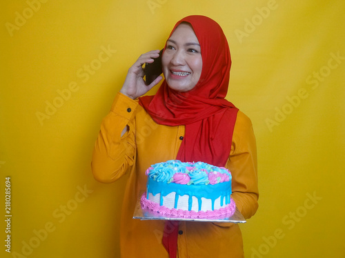 Young Woman In Hijab Holding Birthday Cake While Talking On The Phone