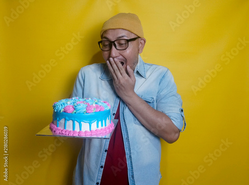 Young Man With Beanie Hat And Glasses Showing Surprise Expression, Cover His Mouth With Hand While Looking At A Sweet Cake