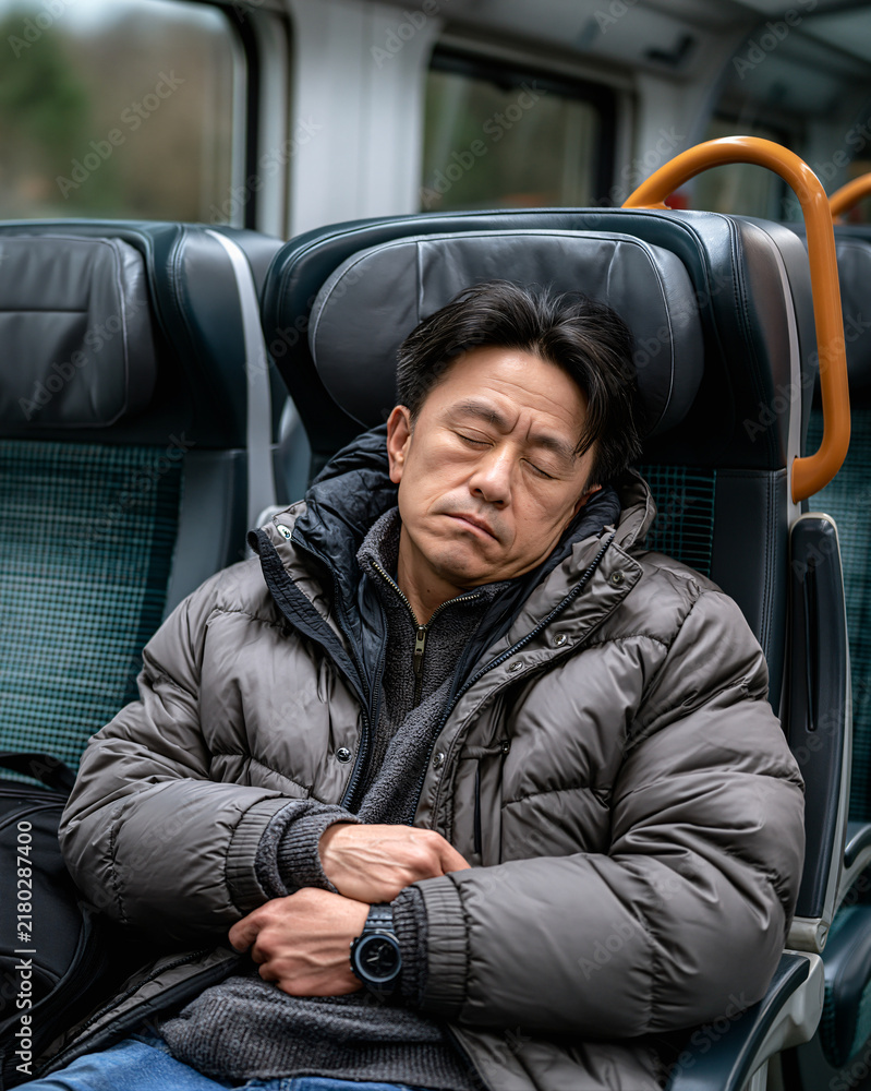 Fototapeta premium Commuter Nap A man sleeps soundly on a train, his head resting gently as he commutes through the day. A moment of quiet repose amidst the journey
