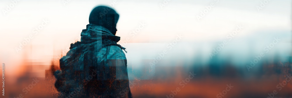 Obraz premium Silhouetted soldier in tactical gear stands in a blurred, muted landscape with a glitch effect and a distant city skyline at sunset.