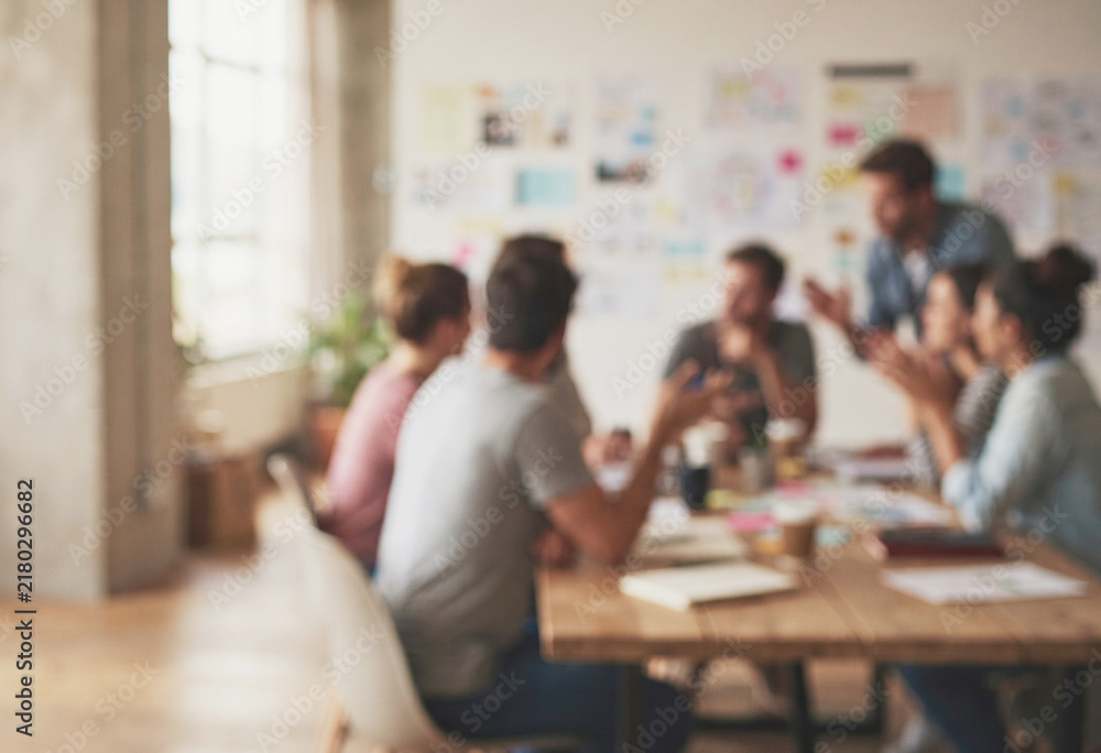 Fototapeta premium Blurred business team collaborates around a table in a bright modern office with sticky notes on the wall.