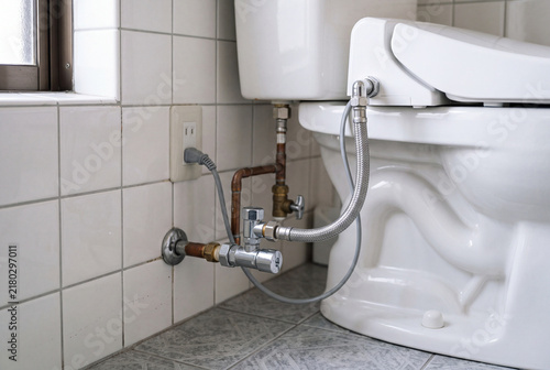Naklejka トイレ横の給水管と止水栓を写した住宅トイレの配管クローズアップ