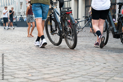 People in the city, pedestrian walking with bicycle on pavement, tourism and travel concept, active lifestyle, leisure activity, shopping street in Trier, Germany