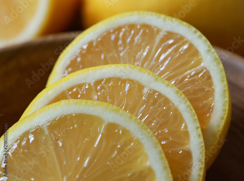 Photography Whole and sliced yellow lemons on wooden bowl.