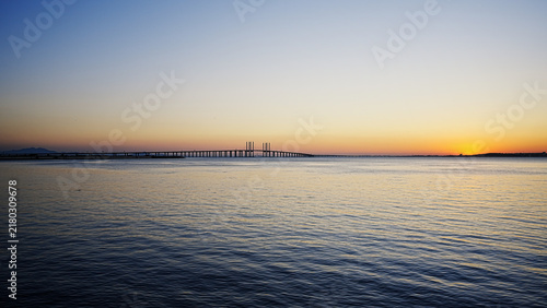 Bild auf Leinwand Silhouetted Bridge Over Calm Water At Sunset