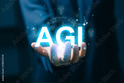 Business professional holds glowing AGI text over a digital globe with chatbot icons, representing artificial general intelligence, global automation, innovation, and intelligent technology.