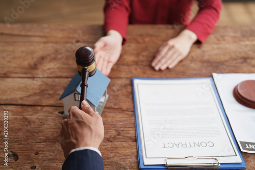 Canvastavla Auctioneer holding gavel over house model, negotiating a real estate contract wi