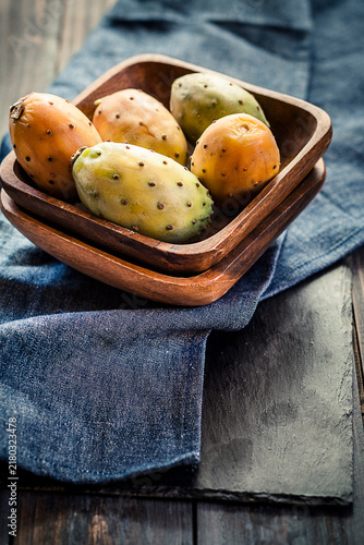 Wooden bowl of prickly pears on cloth and slate