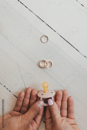 Konstfotografi Hands holding baby pacifier near rings intentional parenthood decision