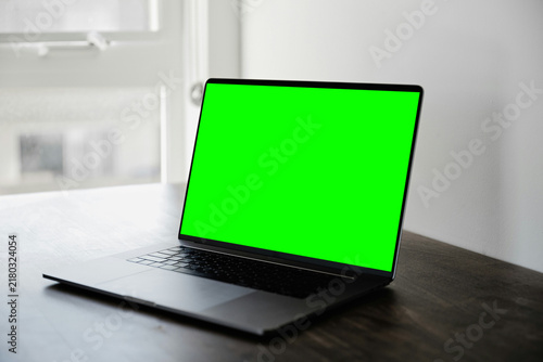 Fotografie Laptop with Green Screen Chroma Key Display on Wooden Desk by Window
