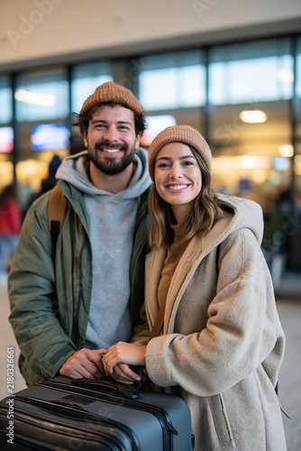 Happy couple reunited at airport holding hands by luggage