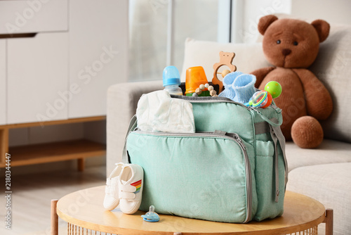 Baby bag with accessories and booties on table in living room