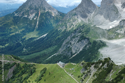 Foto Alpine refuge Dachsteinsuedwandhuette situated on a green ridge below steep rock