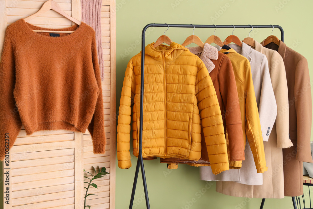 Obraz premium Rack with stylish warm clothes and folding screen in interior of dressing room