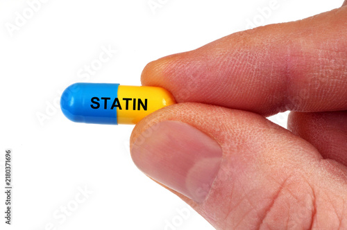 Concept de gélule de statine tenue en main en gros plan isolée sur fond blanc