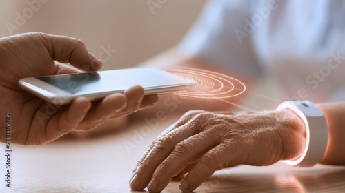 Elderly Emergency Alert Smartphone scanning a wearable device on a person's wrist, symbolizing contactless technology and digital interaction.
