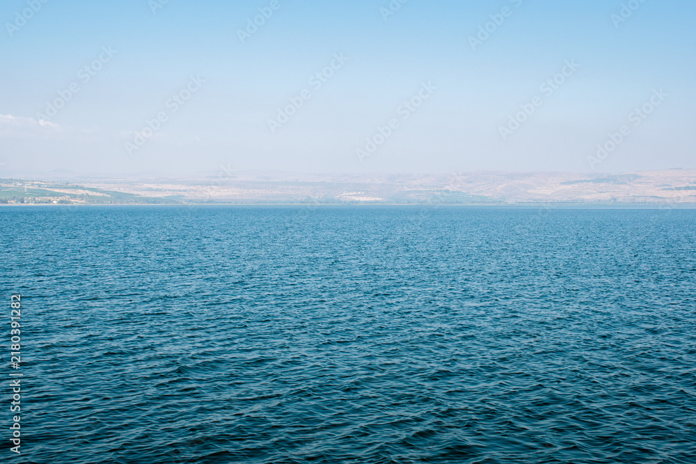 Fototapeta premium Calm blue water of the Sea of Galilee stretching beneath hazy hills in Israel