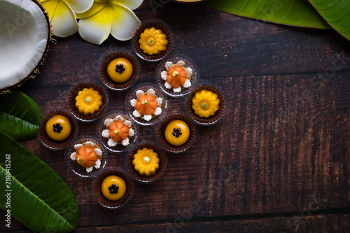 Traditional golden Thai sweets are placed on a wooden table, adorned with banana leaves and flowers