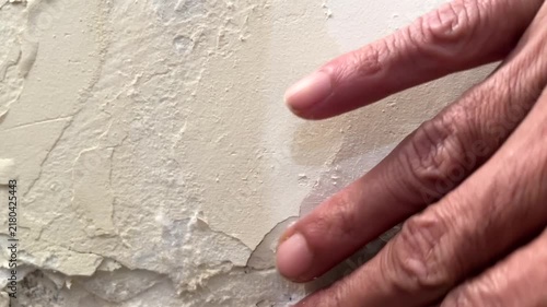 Close up of hand touching peeling paint and damp wall damage