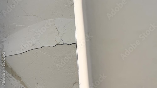 Close up camera panning along horizontal crack on white wall