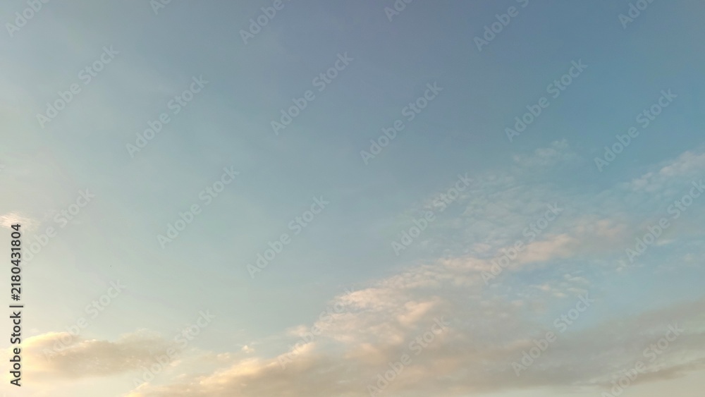 Fototapeta premium Pastel blue sky with softly illuminated clouds