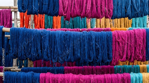 Vibrant colorful dyed yarn hanging to dry on bamboo poles in a textile facility