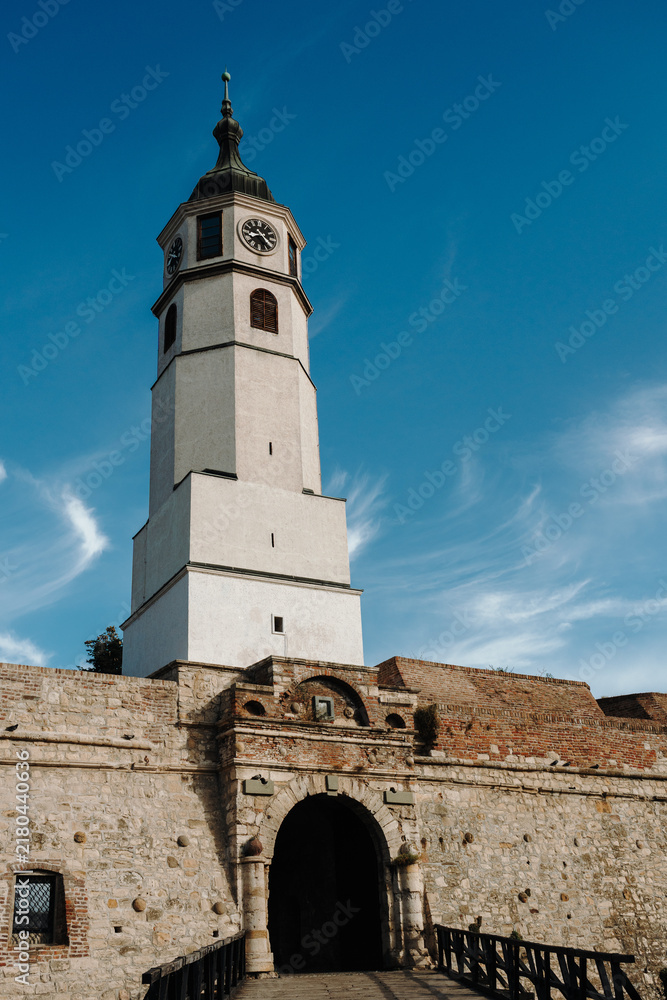 Obraz premium The Sahat Kula clock tower stands above the Sahat Gate and fortress walls in Kalemegdan. Belgrade tourism, heritage and historic architecture concept.
