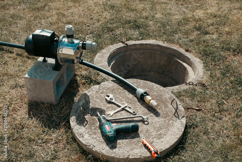 Quadro su tela Tools and suction pipe with brass check valve lying on concrete well cover next
