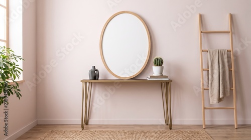 Minimalist interior design of a hallway featuring a wooden console table with metal legs, a large round mirror, a ladder shelf with a towel, and potted plants against a soft pink