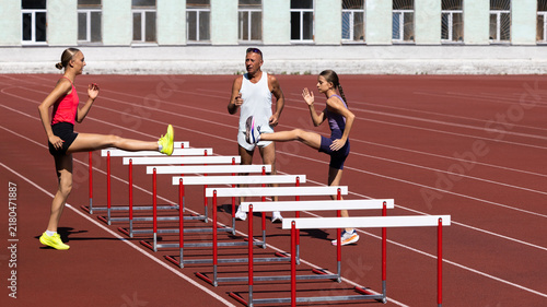 Fotografie Female high jump athletes move through hurdle line during track practice