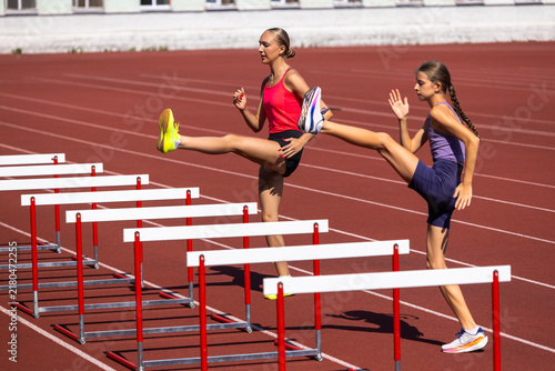 Fotografie Adult and teenage female athletes lift legs over training hurdles