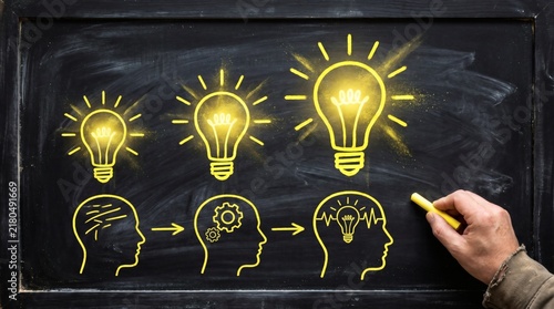Hand pointing to a glowing lightbulb inside a head silhouette